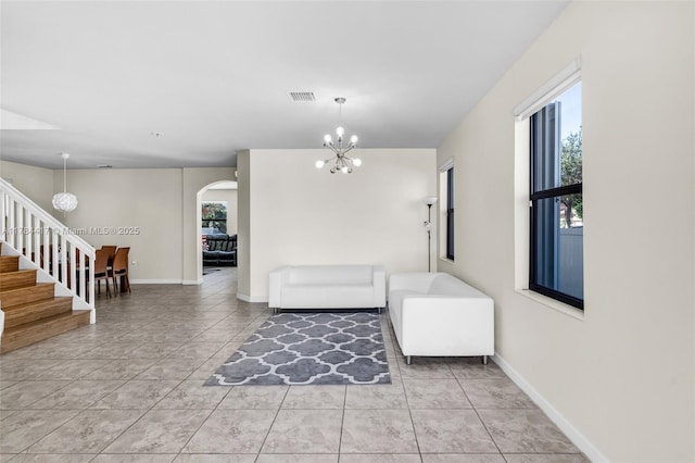 interior space with light tile patterned floors, arched walkways, visible vents, stairway, and a notable chandelier