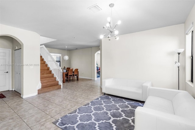 living room featuring light tile patterned floors, an inviting chandelier, arched walkways, visible vents, and stairway