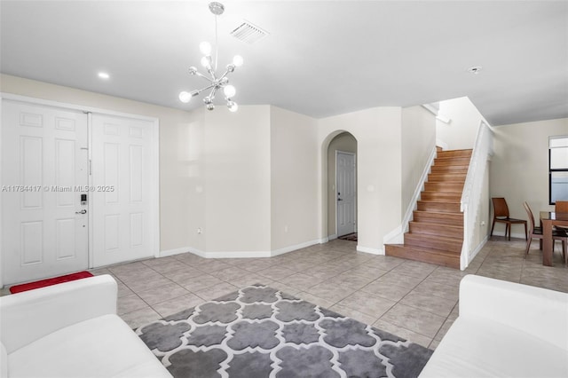 living area with a chandelier, tile patterned floors, stairs, visible vents, and arched walkways