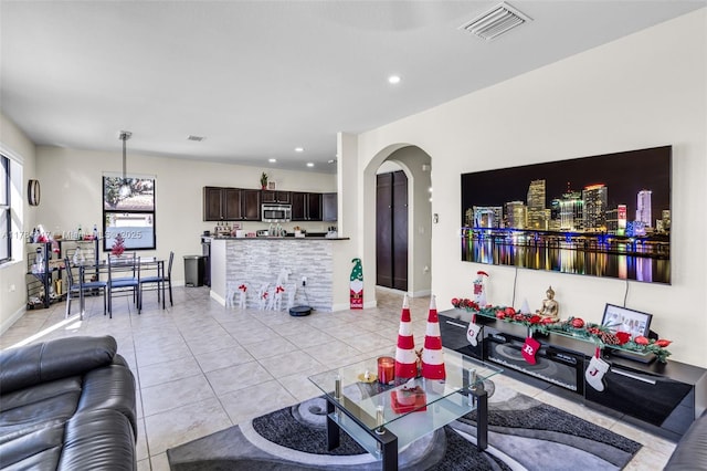 living area with light tile patterned floors, arched walkways, visible vents, recessed lighting, and baseboards