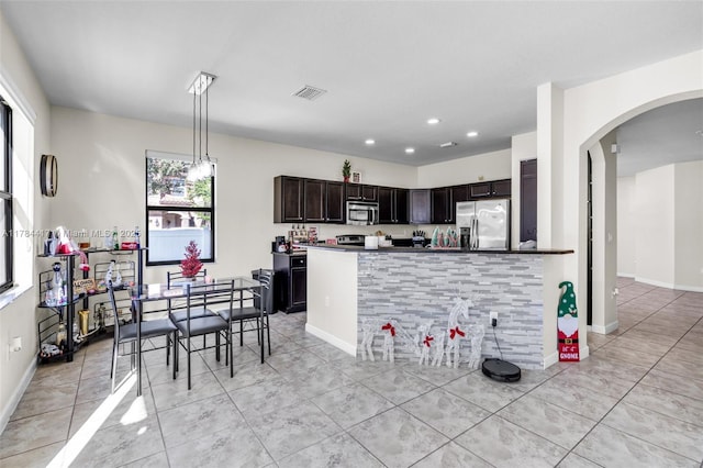 kitchen featuring visible vents, arched walkways, dark countertops, recessed lighting, and stainless steel appliances