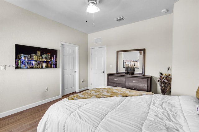 bedroom featuring visible vents, baseboards, ceiling fan, and wood finished floors