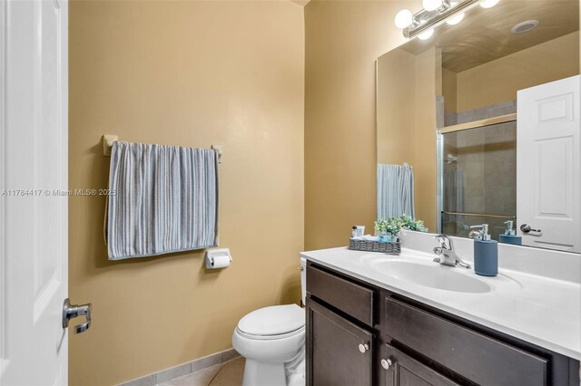 bathroom featuring a shower stall, vanity, tile patterned flooring, and toilet