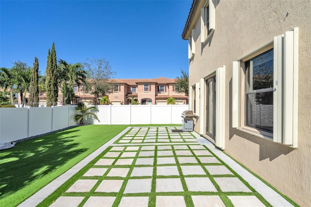 view of yard featuring a fenced backyard, a residential view, and a patio area