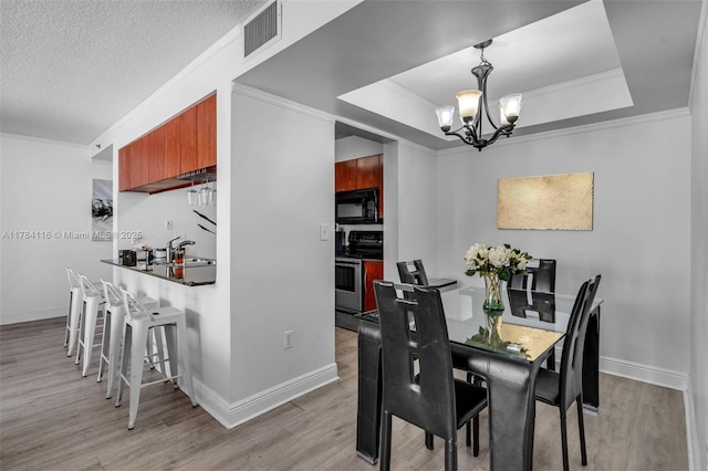 1200 Brickell Bay Dr Unit 1723, Miami, FL 33131 - dining space featuring visible vents, baseboards, a notable chandelier, a tray ceiling, and light wood finished floors