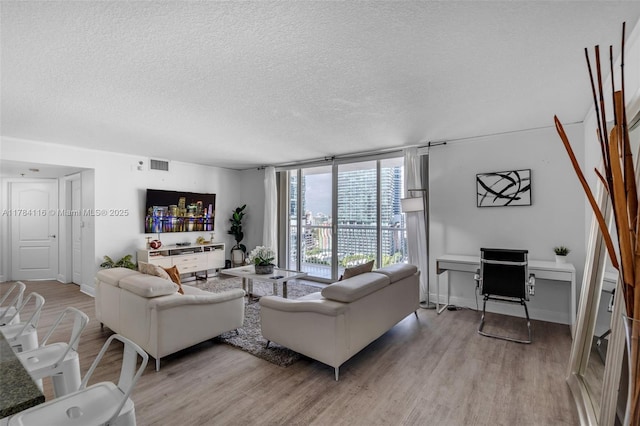 1200 Brickell Bay Dr Unit 1723, Miami, FL 33131 - living room with light wood-type flooring, a textured ceiling, a wall of windows, visible vents, and baseboards
