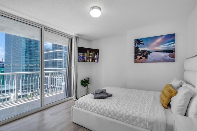 1200 Brickell Bay Dr Unit 1723, Miami, FL 33131 - bedroom with a textured ceiling, wood finished floors, floor to ceiling windows, and access to exterior
