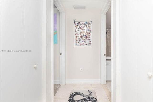 corridor featuring light tile patterned floors, baseboards, and visible vents