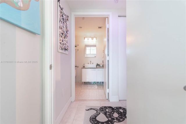 corridor featuring visible vents, a sink, and light tile patterned flooring