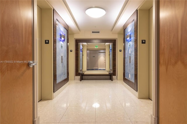 hallway with light tile patterned floors, visible vents, and elevator