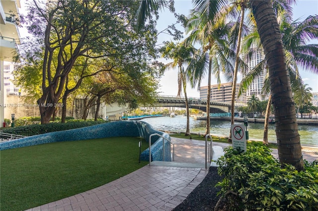 view of property's community with a lawn and a water view