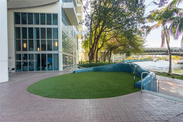 surrounding community with a patio, a yard, curved driveway, and a water view