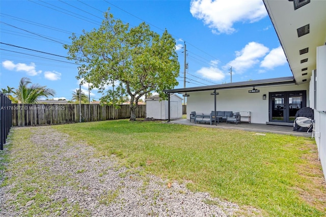 view of yard with a shed, outdoor lounge area, a fenced backyard, an outbuilding, and french doors