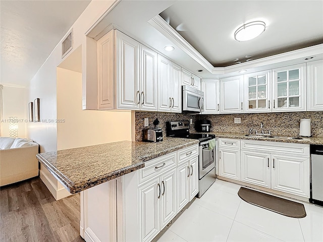 1913 S Ocean Dr Unit 110, Hallandale Beach, FL 33009 - kitchen featuring white cabinets, stainless steel appliances, visible vents, and glass insert cabinets