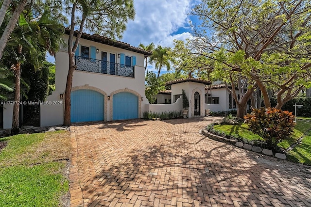 551 S Mashta Dr, Key Biscayne, FL 33149 - mediterranean / spanish-style house featuring a tiled roof, a balcony, stucco siding, decorative driveway, and a garage