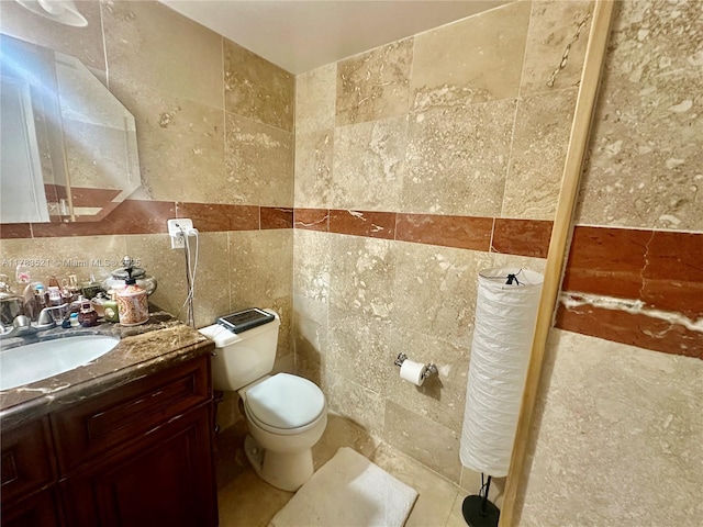 bathroom with toilet, tile walls, and vanity