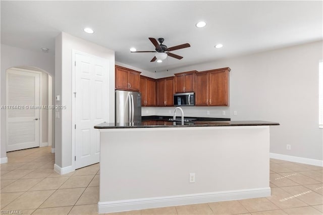 19726 Tesoro Way, Estero, FL 33967 - kitchen featuring ceiling fan, dark countertops, arched walkways, light tile patterned floors, and stainless steel appliances