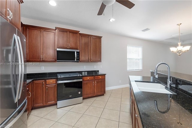 19726 Tesoro Way, Estero, FL 33967 - kitchen with hanging light fixtures, a sink, ceiling fan with notable chandelier, dark stone counters, and stainless steel appliances