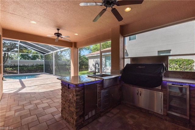 19726 Tesoro Way, Estero, FL 33967 - view of patio / terrace featuring ceiling fan, glass enclosure, wine cooler, an outdoor kitchen, and a grill