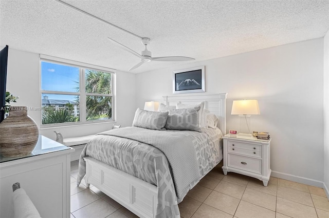 bedroom with baseboards, light tile patterned floors, a textured ceiling, and a ceiling fan
