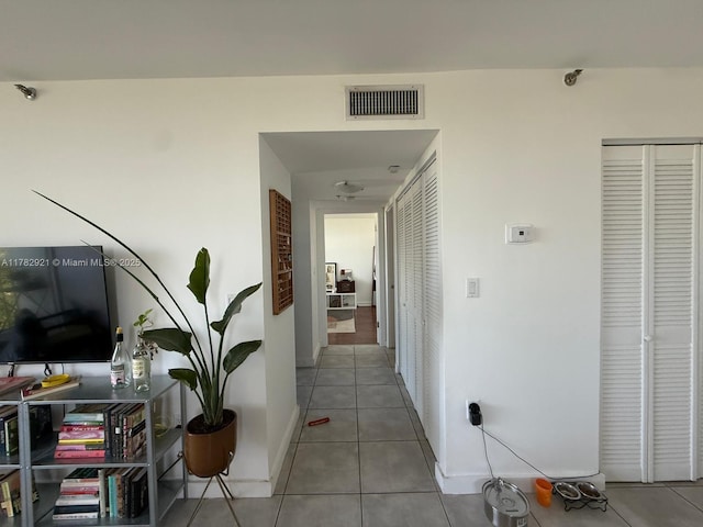 hall with tile patterned floors, visible vents, and baseboards