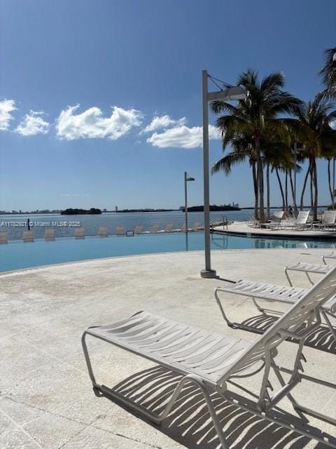 view of swimming pool featuring a patio and a water view