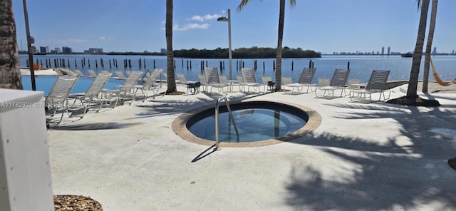 view of swimming pool with a patio area, a hot tub, and a water view