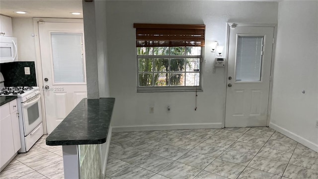 525 Meridian Ave Unit 105, Miami Beach, FL 33139 - kitchen with white appliances, white cabinets, marble finish floor, dark countertops, and baseboards