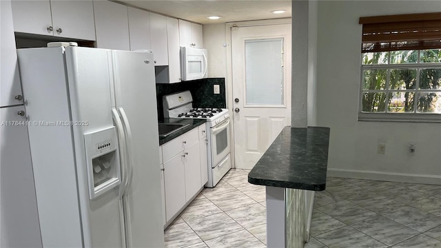 525 Meridian Ave Unit 105, Miami Beach, FL 33139 - kitchen with white appliances, dark countertops, white cabinets, decorative backsplash, and marble finish floor