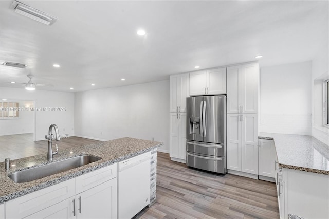 kitchen featuring white cabinetry, visible vents, stainless steel refrigerator with ice dispenser, dishwasher, and a sink