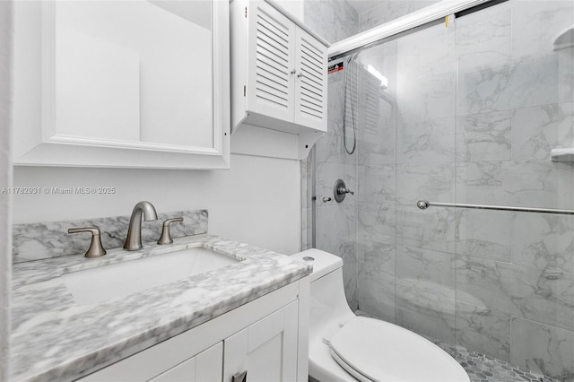 bathroom with toilet, a shower stall, and vanity