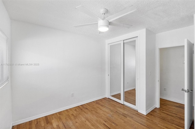 unfurnished bedroom with a closet, baseboards, a ceiling fan, a textured ceiling, and light wood-style flooring