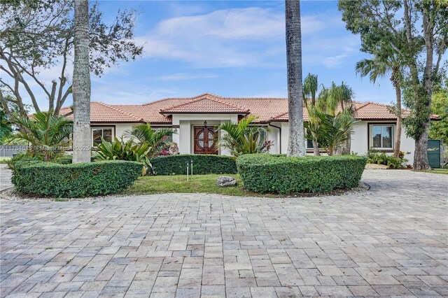 view of front facade with stucco siding, a tiled roof, and decorative driveway