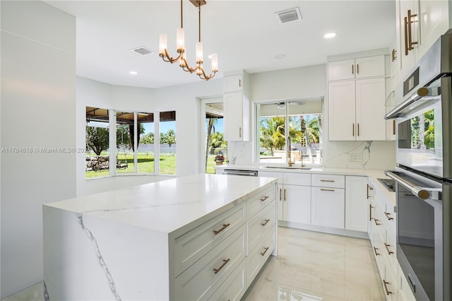 kitchen with a chandelier, a wealth of natural light, light stone countertops, and double oven