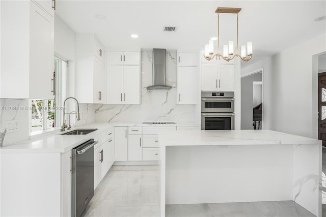 kitchen with wall chimney exhaust hood, a chandelier, marble finish floor, a sink, and stainless steel appliances
