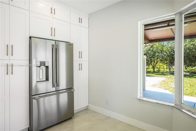 kitchen with high end refrigerator, baseboards, and white cabinetry