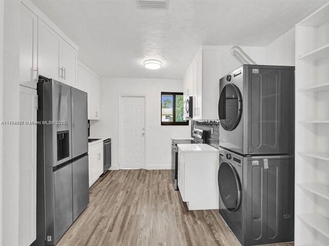 1021 NE 110th St, Biscayne Park, FL 33161 - clothes washing area with laundry area, visible vents, wood finished floors, baseboards, and stacked washer / drying machine