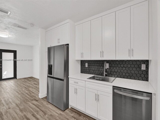 1021 NE 110th St, Biscayne Park, FL 33161 - kitchen with visible vents, light wood-style floors, tasteful backsplash, a sink, and stainless steel appliances