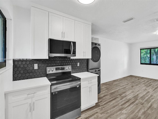 1021 NE 110th St, Biscayne Park, FL 33161 - kitchen with stacked washing maching and dryer, appliances with stainless steel finishes, backsplash, and visible vents