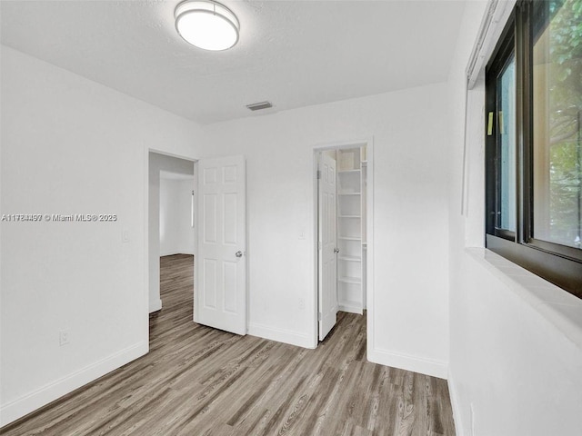 1021 NE 110th St, Biscayne Park, FL 33161 - unfurnished bedroom featuring baseboards, a walk in closet, wood finished floors, and visible vents