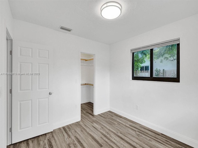 1021 NE 110th St, Biscayne Park, FL 33161 - unfurnished bedroom featuring a spacious closet, baseboards, wood finished floors, and visible vents