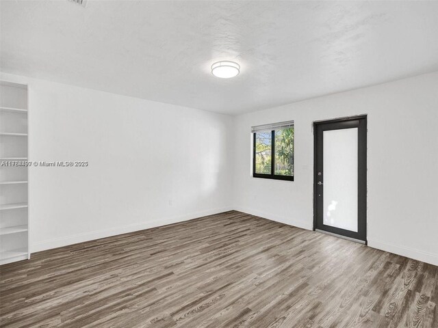 1021 NE 110th St, Biscayne Park, FL 33161 - empty room featuring built in features, baseboards, and wood finished floors
