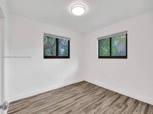 1021 NE 110th St, Biscayne Park, FL 33161 - spare room featuring baseboards, wood finished floors, and a healthy amount of sunlight
