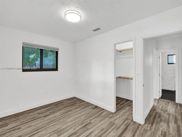 1021 NE 110th St, Biscayne Park, FL 33161 - unfurnished bedroom with a walk in closet, visible vents, wood finished floors, baseboards, and a closet