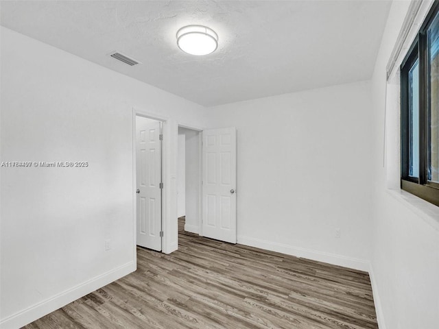 1021 NE 110th St, Biscayne Park, FL 33161 - unfurnished bedroom featuring baseboards, a textured ceiling, wood finished floors, and visible vents