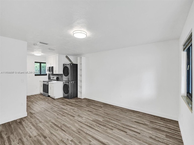 1021 NE 110th St, Biscayne Park, FL 33161 - unfurnished living room with wood finished floors, baseboards, stacked washer / drying machine, and visible vents