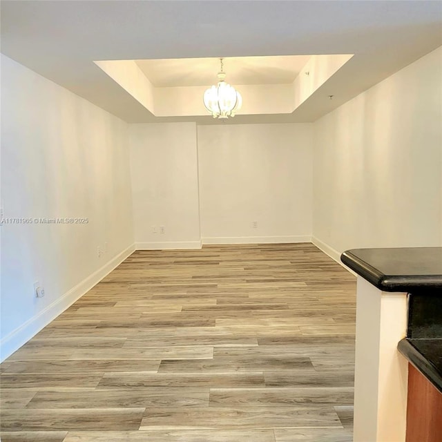 14951 Royal Oaks Ln Unit 203, North Miami, FL 33181 - unfurnished dining area featuring light wood-style flooring, a raised ceiling, an inviting chandelier, and baseboards