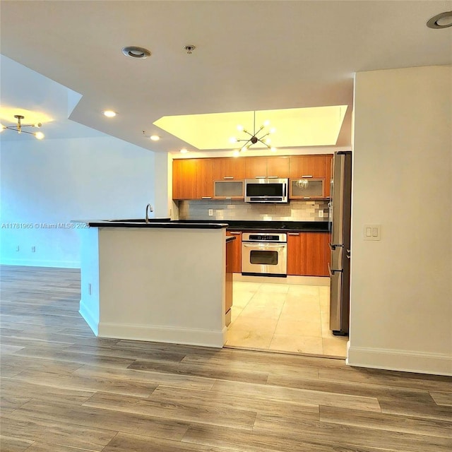 14951 Royal Oaks Ln Unit 203, North Miami, FL 33181 - kitchen with a chandelier, dark countertops, brown cabinets, and appliances with stainless steel finishes