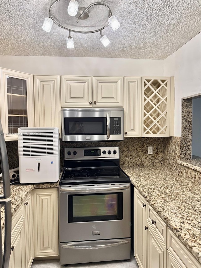 900 Atlantic Shores Blvd Unit 126, Hallandale Beach, FL 33009 - kitchen featuring stainless steel appliances, a textured ceiling, cream cabinetry, light stone counters, and tasteful backsplash