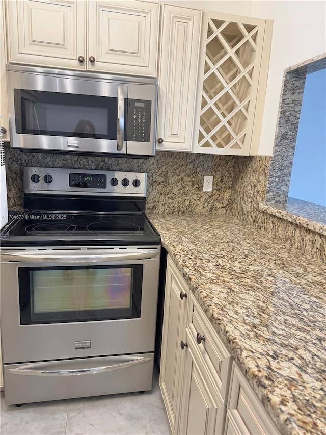 900 Atlantic Shores Blvd Unit 126, Hallandale Beach, FL 33009 - kitchen featuring appliances with stainless steel finishes, light stone countertops, backsplash, and cream cabinets